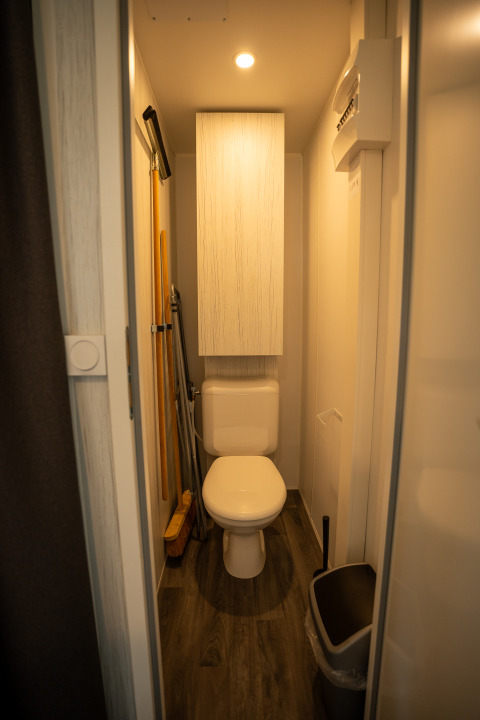Compacte badkamer met toilet, schoonmaakgerei, kast en vuilnisbak in Cooc tent deluxe, Familiepark Goolderheide.
