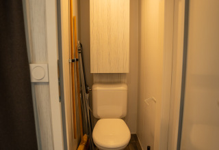 Compacte badkamer met toilet, schoonmaakgerei, kast en vuilnisbak in Cooc tent deluxe, Familiepark Goolderheide.