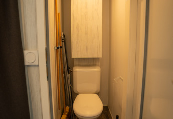 Petite salle de bains avec toilettes, armoire, outils de nettoyage et poubelle au Cooc tent deluxe, Familiepark Goolderheide.