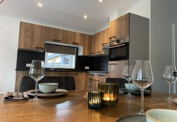 Modern lodge kitchen and dining table with candles at Wood Cottage, De Witte Berg holiday park, Netherlands.