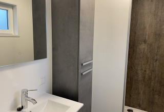 Modern bathroom in Wood Cottage at Holiday Park De Witte Berg featuring a sink, mirror, and shower stall.