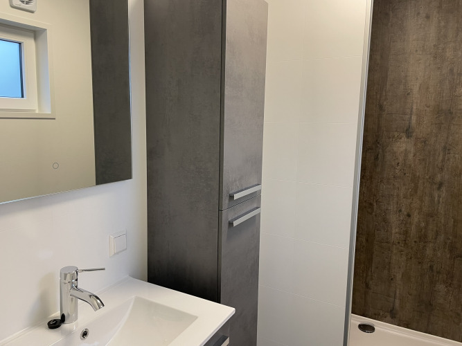 Modernes Bad im Wood Cottage im Holiday Park De Witte Berg mit Waschbecken, Spiegel und Dusche.