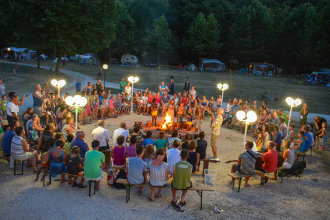 Groepsbijeenkomst rond een kampvuur bij La Draille, een vakantiepark in Occitanië, Frankrijk.