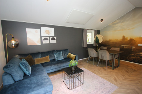 Woonruimte van Velthorst Hottub lodge bij EuroParcs Ruinen, Nederland, met blauwe zetel en eettafel.