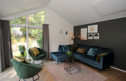 Bright, modern living room in the Velthorst lodge at EuroParcs Ruinen, Netherlands, with large windows and elegant decor.