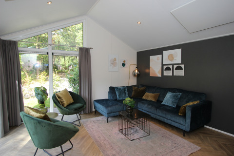 Lichte, moderne woonkamer in de Velthorst-lodge bij EuroParcs Ruinen, met grote ramen en stijlvolle inrichting.