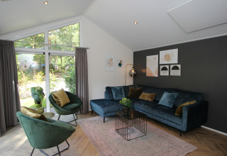 Lichte, moderne woonkamer in de Velthorst-lodge bij EuroParcs Ruinen, met grote ramen en stijlvolle inrichting.