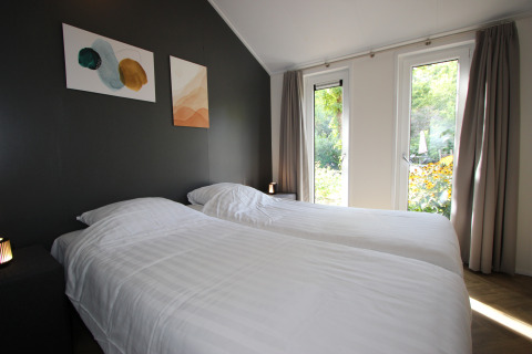 Moderne slaapkamer met twee eenpersoonsbedden, grote ramen en tuinzicht, Velthorst Hottub, EuroParcs Ruinen.