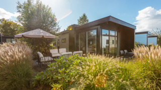 Espace extérieur du lodge Vakantiechalet Comfort+ avec terrasse, mobilier de jardin et plantes au soleil.