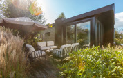 Terraza soleada en Vakantiechalet comfort+ con asientos y sombrilla en De Wiedense Meren, Países Bajos.