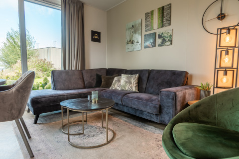 Salon moderne du Vakantiechalet comfort+ à Vakantiepark De Wiedense Meren avec canapé et œuvre murale.