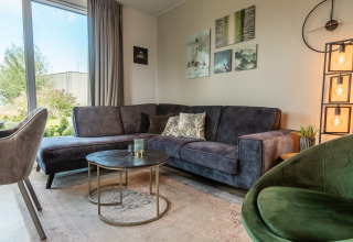 Soggiorno elegante nel Vakantiechalet comfort+ al Vakantiepark De Wiedense Meren con divano e decorazioni.