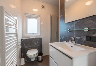 Salle de bains moderne avec WC suspendu, lavabo, et douche au Vakantiechalet comfort+ aux Pays-Bas.