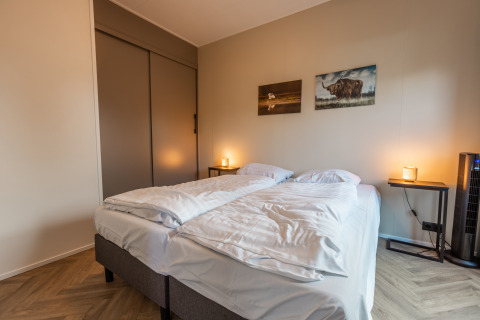 Modernes Schlafzimmer mit zwei Einzelbetten, Kunst an der Wand und sanfter Beleuchtung im Chalet.