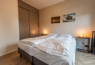 Camera da lodge con due letti singoli, quadri alle pareti e luci soffuse al Vakantiechalet comfort+ nei Paesi Bassi.