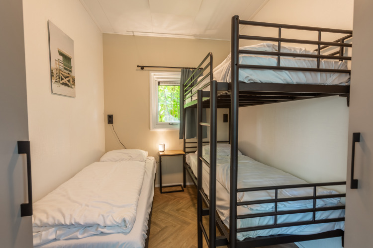 Helles Schlafzimmer mit Stockbett und Einzelbett im Vakantiechalet comfort+ im Vakantiepark De Wiedense Meren.