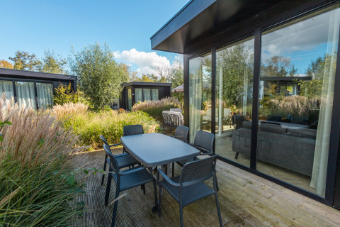 Terrazza esterna con tavolo e sedie al Vakantiechalet comfort+ nel Vakantiepark De Wiedense Meren, Paesi Bassi.