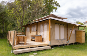Tienda safari Stardust 40 Family Lodge con terraza de madera, muebles exteriores y entorno verde.