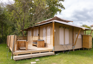Tente safari Stardust 40 Family Lodge avec terrasse en bois, mobilier d'extérieur et verdure environnante.