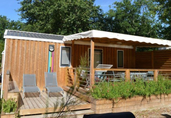 Vista esterna della Stacaravan Premium Clim al Flower Camping La Canadienne con terrazza in legno e lettini.