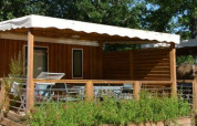 Stacaravan Premium Clim bei Flower Camping La Canadienne in Frankreich mit Holzterrasse und viel Grün.