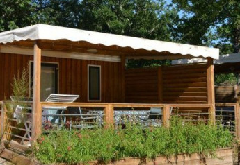Stacaravan Premium Clim bij Flower Camping La Canadienne in Frankrijk met houten terras en groene beplanting.