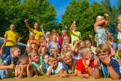 Groep kinderen en volwassenen met duimen omhoog poseren buiten op een zonnige dag in La Draille, Frankrijk.