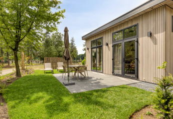 Buitenterras bij een moderne lodge op Bospark Ede, Nederland, met tuinmeubilair en een groene grasmat.