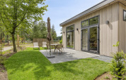 Terrasse extérieure d’un lodge moderne à Bospark Ede, Pays-Bas, avec mobilier de jardin et pelouse verte.