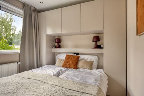 Dormitorio moderno en la cabaña Heideveld de Bospark Ede, Países Bajos, con cama y armarios empotrados.
