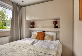 Moderne slaapkamer in Heideveld-lodge bij Bospark Ede, Nederland, met bed en ingebouwde kastruimte.