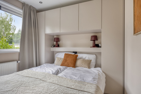 Moderne slaapkamer in Heideveld-lodge bij Bospark Ede, Nederland, met bed en ingebouwde kastruimte.
