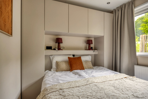 Dormitorio moderno en la cabaña Heideveld en Bospark Ede, Países Bajos, con armarios empotrados y cama doble.