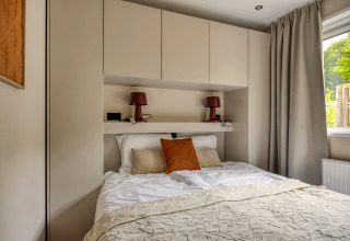 Dormitorio moderno en la cabaña Heideveld en Bospark Ede, Países Bajos, con armarios empotrados y cama doble.