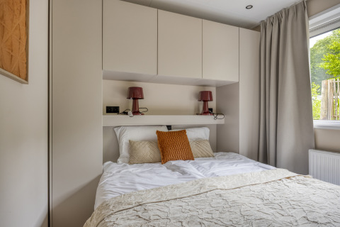 Moderne slaapkamer in Heideveld lodge op Bospark Ede in Nederland, met inbouwkasten en tweepersoonsbed.