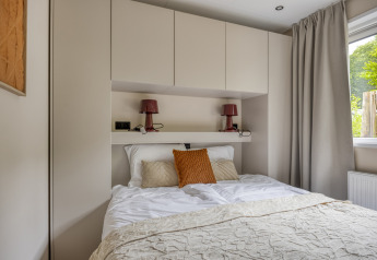 Moderne slaapkamer in Heideveld lodge op Bospark Ede in Nederland, met inbouwkasten en tweepersoonsbed.