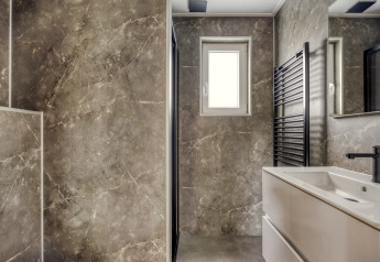 Moderne badkamer met marmeren muren, raam, wastafel en zwarte handdoekradiator in Heideveld, Bospark Ede.