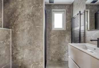 Salle de bain moderne avec murs en marbre, fenêtre, lavabo et sèche-serviettes noir à Heideveld, Bospark Ede, Pays-Bas.