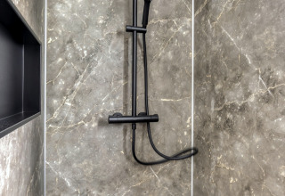 Ducha moderna con paredes efecto mármol oscuro y accesorios negros en Heideveld, Bospark Ede, Países Bajos.