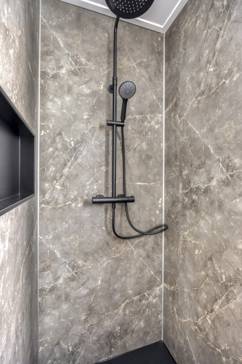 Douche moderne aux murs effet marbre foncé et robinetterie noire à Heideveld, Bospark Ede, Pays-Bas.