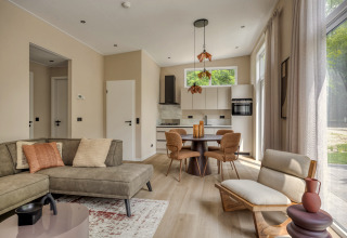 Salón de lodge moderno y luminoso con cocina abierta y grandes ventanales en Heideveld, Bospark Ede, Países Bajos.