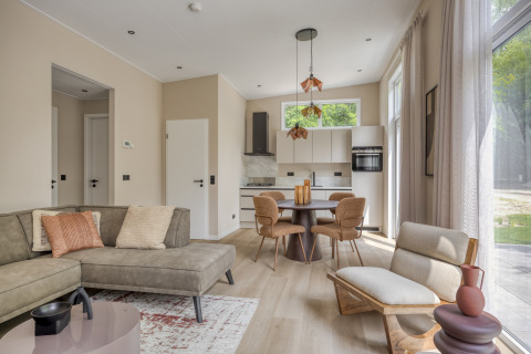 Salón de lodge moderno y luminoso con cocina abierta y grandes ventanales en Heideveld, Bospark Ede, Países Bajos.