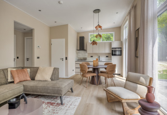 Salón de lodge moderno y luminoso con cocina abierta y grandes ventanales en Heideveld, Bospark Ede, Países Bajos.