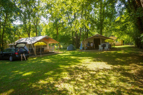 Kampeerplaatsen bij La Draille vakantiepark in Occitanië, Frankrijk, met tenten en zomerzon in het bos.