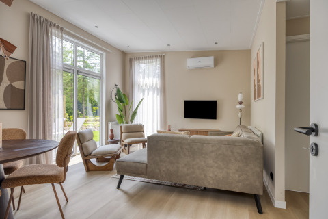 Modern living room at Heideveld lodge, Bospark Ede, Netherlands, with large windows and natural light.