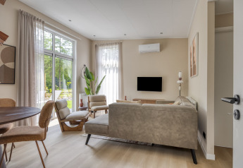 Modernes Wohnzimmer in der Lodge Heideveld, Bospark Ede, Niederlande, mit großen Fenstern.