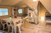 Interior de la tienda Safaritent en Glyngore Camping, Dinamarca, con muebles de madera y camas.