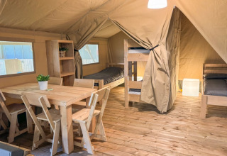 Interior of Safaritent at Glyngore Camping in Denmark featuring wooden furniture, beds, and flooring.