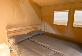 Doppelbett im gemütlichen Safarizelt mit zwei Fenstern bei Glyngore Camping in Dänemark.