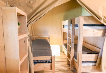 Indvendigt billede af en Safaritent ved Glyngore Camping i Danmark med køjesenge og trægulv.